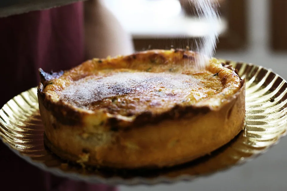 Flaó ibicenco entero sobre una bandeja dorada, espolvoreado con azúcar glas.