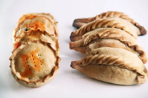 Panades y cocarrois recién hechos, con el borde repulgado a mano.
