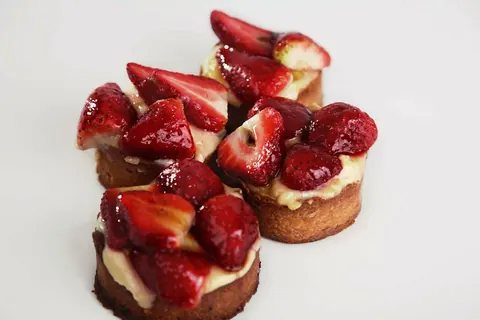 Tartaletas de fresa con crema pastelera y fresas frescas cortadas por encima.